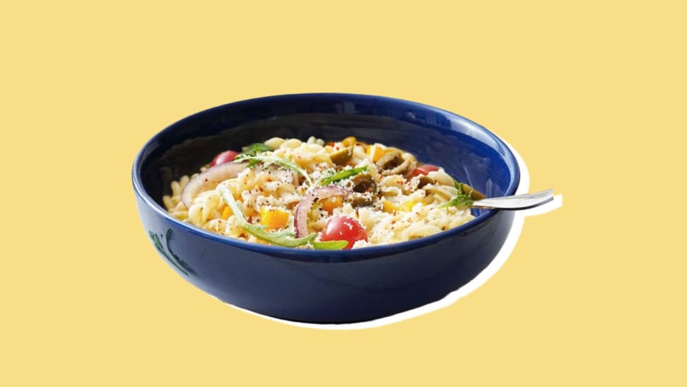 A navy blue bowl holding pasta and a fork.