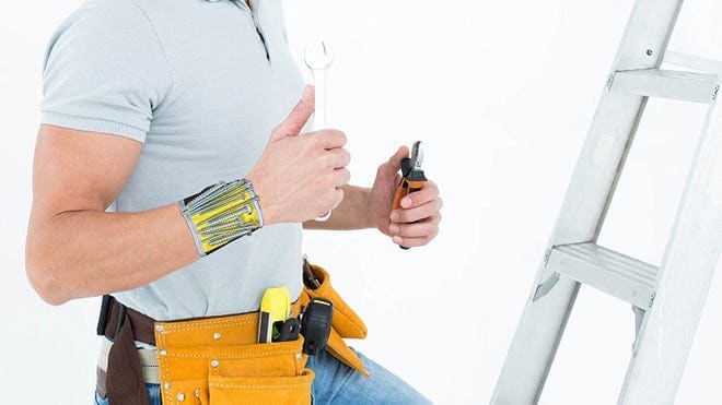 Person holding tools wearing magnetic wristband for tools