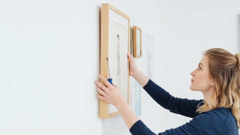 Woman hanging up framed art