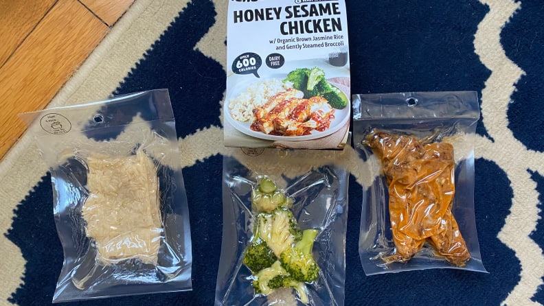 This image displays what's inside a Honey Sesame Chicken premade meal kits, a bag of brown rice, a bag of cooked broccoli, and a bag of sesame chicken.
