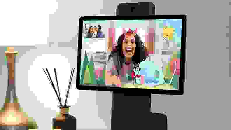 An iPad and webcam are set up for a family to communicate virtually. The Facebook Portal app adds silly facial effects and cartoony backdrop elements.