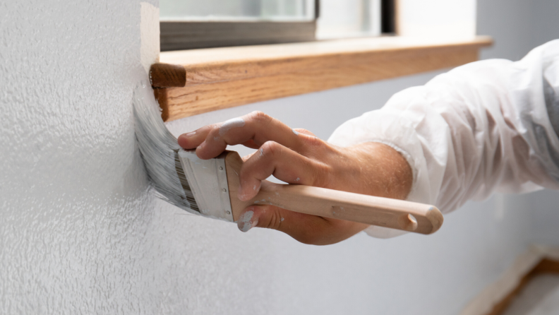 Person touching up a paint job around a window