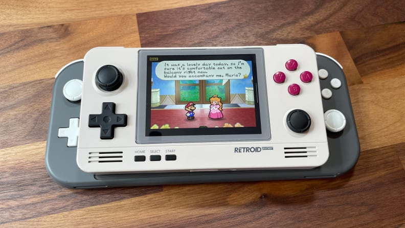 The Retroid Pocket 2+ laid on a table with a Super Mario game paused.