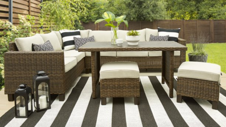 A patio set sitting on an outdoor rug with a backyard in the background.