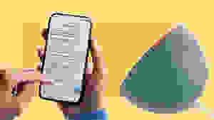 A person holding a smart phone next to an Alexa.