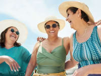 Three people in sun hats and sunglasses laughing