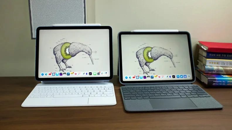 Two tablets with attached keyboards sit next to each other on a wooden table.