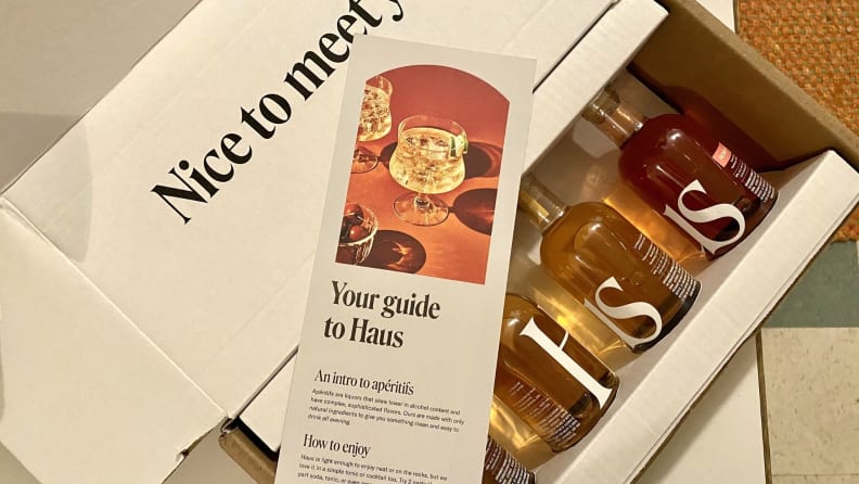 A top-down photo of a white cardboard box containing four mini bottles of Haus aperitifs.