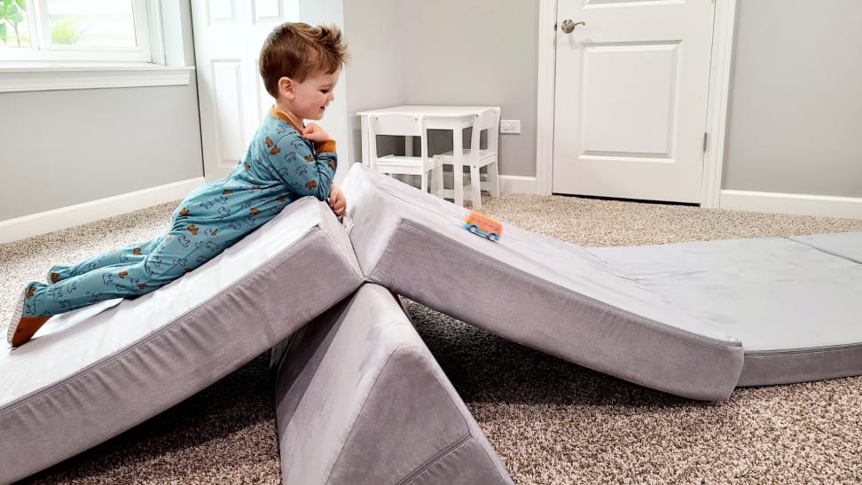 A child plays on a Nugget couch with a toy car.