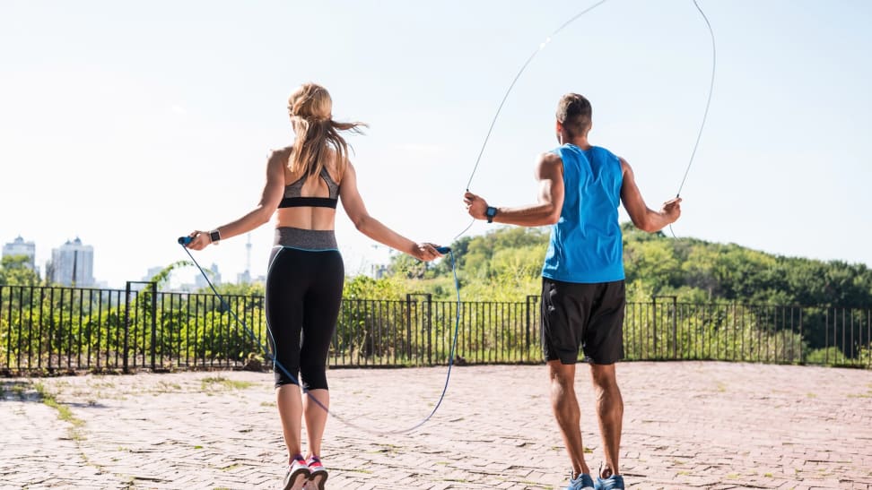 Man and woman jumping rope outside and overlooking city.