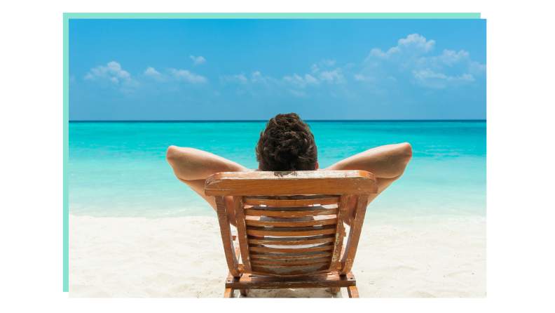 The backside of a person sitting in a chair facing the ocean.