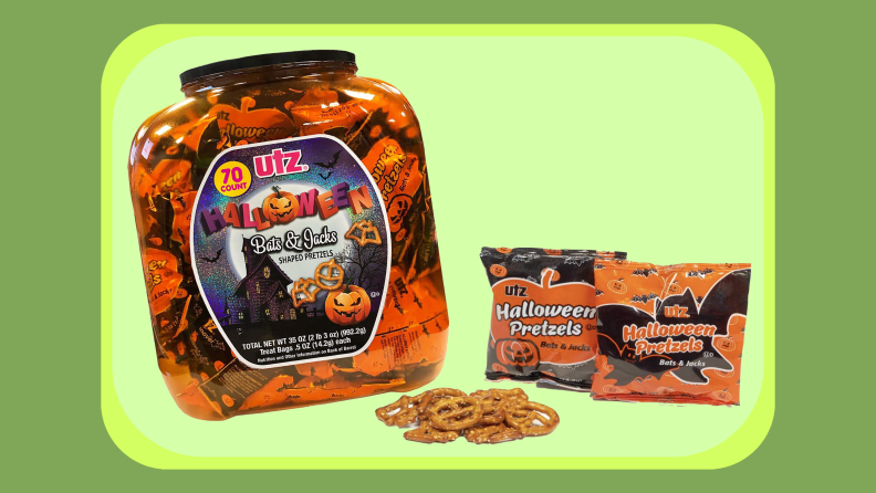 Clear, plastic jar filled with numerous small packages of pretzels next to pile of pretzels and two more packages of pretzels.