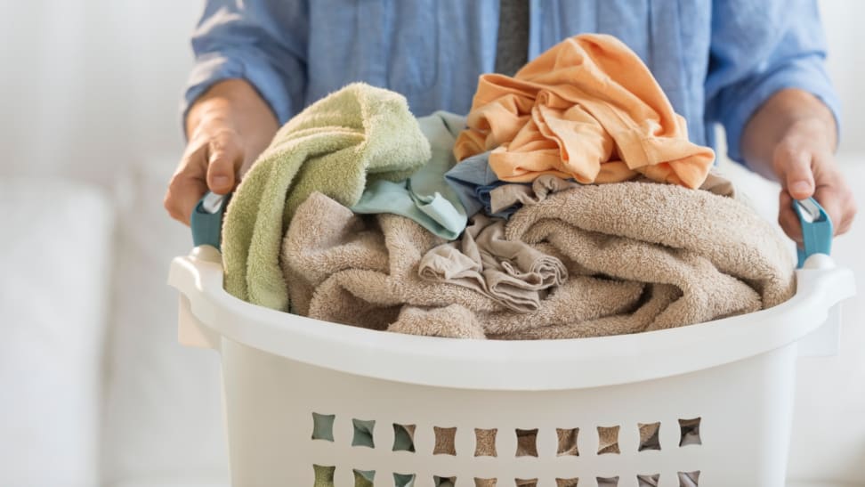 Man holding laundry basket filled with clothes.