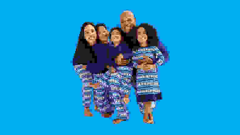A family wearing the Jammies For Your Families Winter Wonderland Pajama Collection on a blue background.