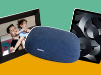 Digital picture frame with parent and child smiling together inside the black frame next to navy blue weighted pillow next to black Apple iPad tablet.