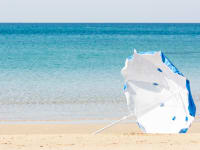 A blue and white umbrella blows in the wind