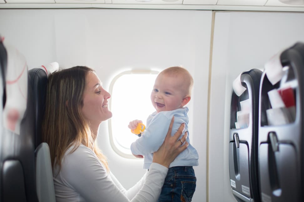 Young mom, playing with her toddler boy on board an airplane while going on a trip.