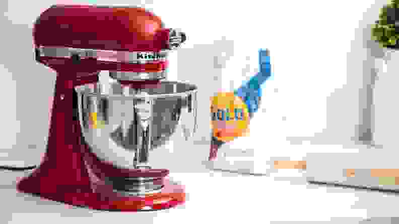 A red KitchenAid stand mixer on a kitchen counter next to flour and a rolling pin.