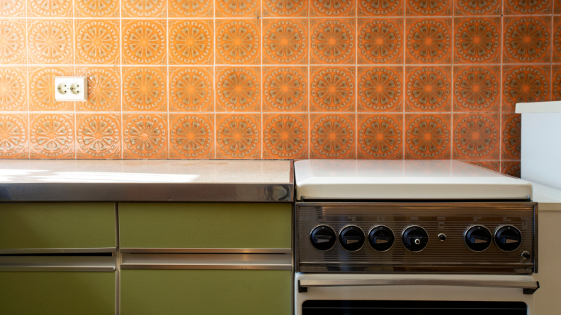 A old kitchen with vintage tiling, appliances, and counters.