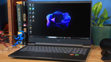 The HP Victus 16 sitting atop a desk with a multitude of books and two Halo Spartan figures.