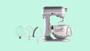 A silver KitchenAid Stand Mixer along with a whisk and two flat attatchments, set against a mint green background.