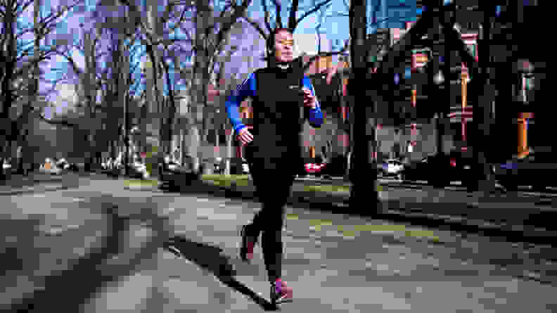 A woman running down the street wearing a Nike vest.