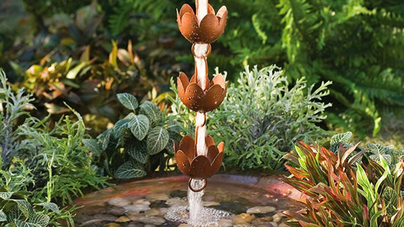 A copper rain chain pours water into a bucket.