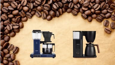 Two coffee pots sit on a beige background surrounded by coffee beans