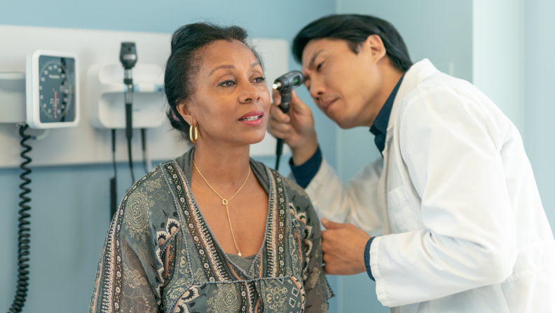 A doctor examines a patient’s ears.