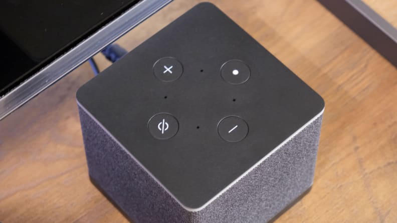 The control buttons on top of the Amazon Fire TV Cube sitting on a wooden table.