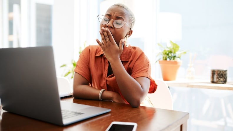 a person sits and yawns by their computer